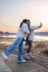 Walk along the promenade. A walk by the sea. Women taking photos at sunset.