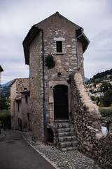 Fototapeta premium Old town, stone building, Chinese wisteria growing on stone walls and blooming profusely with purple flowers. View of the old town of Vence in France