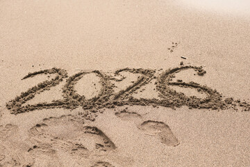 The inscription 2026 on the sandy beach. Numbers in the sand