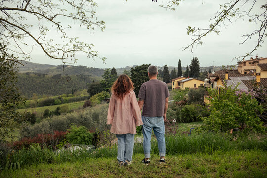 Couple in love admiring the view of Tuscan nature. Beautiful landscape of Italian Tuscany, woman and man standing with their backs to the camera admiring the scenery