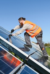 Technician installing solar panels in large solar farm