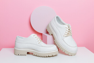 Female stylish footwear on podium at pink background. Leather lace up office shoes, minimal style