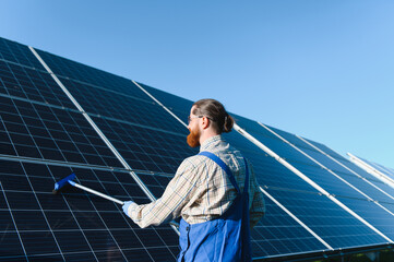 Technician cleaning solar panels in a solar farm for green energy production