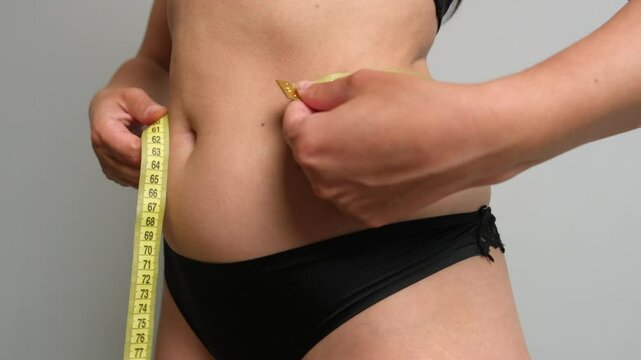 Fitness motivation moment. Woman checking her body with measuring tape and realizing she needs more progress.