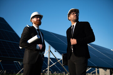 Engineers inspecting solar panel farm for renewable energy