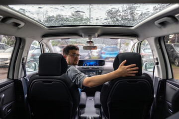 Car interior with driver. Rear seat view. Panoramic roof in the rain.