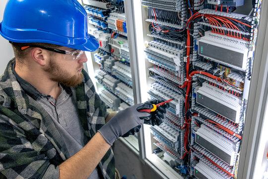 Electrician at work. Electrical panel wiring. Screwdriver installation.
