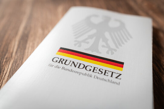 Gedrucktes Exemplar des Grundgesetzes f&uuml;r die Bundesrepublik Deutschland auf Holzuntergrund. Symbolisiert Rechtsstaat, Verfassung, Demokratie und staatliche Ordnung.