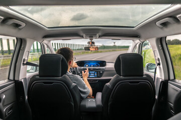 Car interior with panoramic roof. Driver on highway. Road trip.