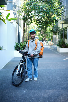 Young Asian delivery boy with his bicycle on the street.