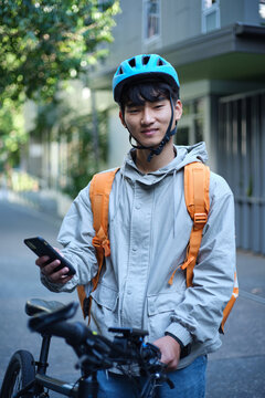 Young Asian delivery boy with his bicycle on the street.