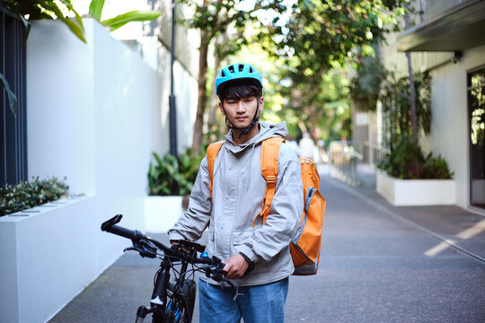 Young Asian delivery guy with his bicycle on the street