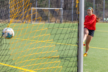 Sporty girl scores a goal into the goal. Football concept. Girl on the football field.