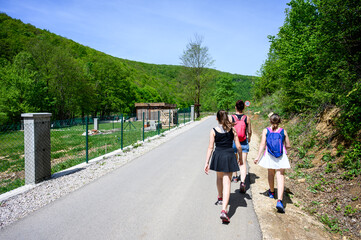Family hiking or walking on a road to visit the famous Strbacki buk waterfall in Bosnia. Hiking in nature wearing sports clothes.