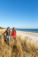 Two women walking on the seashore. Two friends enjoying and spending time together.