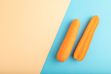 Orange Carrot on orange and blue pastel paper, Top view, copy space