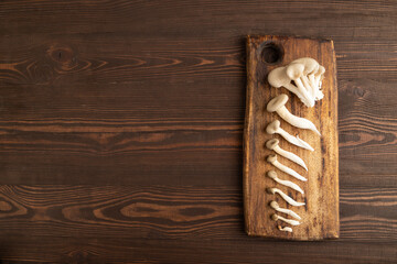 Raw Oyster mushroom, Pleurotus ostreatus on cutting board on brown wooden, Top view, copy space
