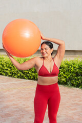 Latin woman doing pilates with fitness ball outdoors