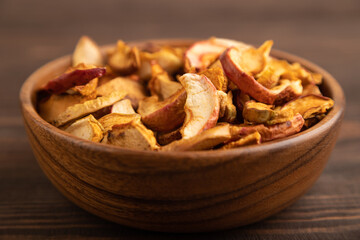 Dried Apples in wooden bowl on brown wooden. Side view, close up, selective focus