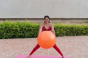 Latin woman doing pilates with an exercise ball outdoors