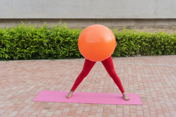 Woman doing pilates with fitness ball in a park