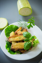 Zucchini with a crispy crust and fresh salad on a gray background