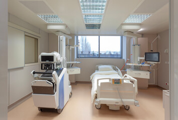 An empty, high-tech hospital room equipped with advanced medical monitoring and treatment equipment.