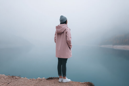solitary human figure stands on coastal cliff in austria enveloped in mist and soft natural light