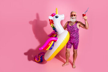 Photo of cheerful positive man wear swimwear enjoy relax rest vacation resort inflatable toy isolated on pink color background