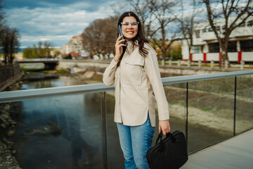 Fototapeta premium Young caucasian woman walk home from work drink coffee and use smartphone 