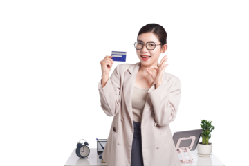 Asian businesswoman poses with bank card in hand, behind her is a table with lots of documents