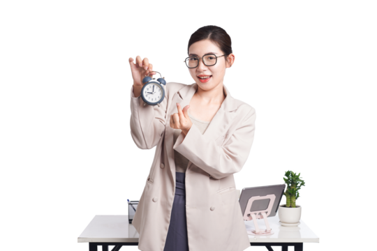 Asian businesswoman holding alarm clock and pointing, reminding of time management with cheerful expression