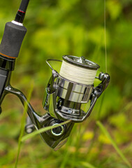 Fishing reel close-up. spinning rod and reel against the background of grass. High quality photo