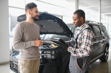 A satisfied client takes his repaired car to the mechanic. Car service station