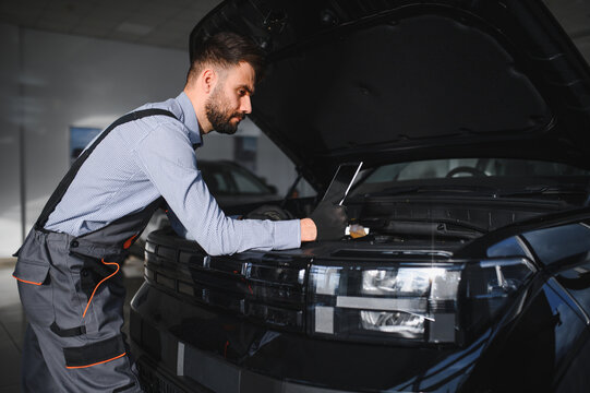 Mechanic Uses a Computer with an Augmented Reality Diagnostics Software. Specialist Inspecting Car's Engine to Quickly Spot Broken Components. Premium Car Service