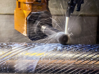 Metal cutting process in a workshop with water coolant spraying on a rotating shaft