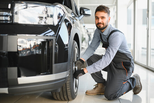 Car mechanic working in garage and changing wheel alloy tire. Repair or maintenance auto service. Replacement of winter and summer tires - Powered by Adobe