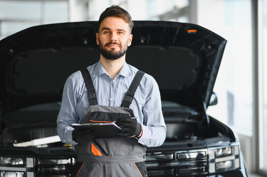 Auto mechanic holding clipboard checklist the car at mechanic shop