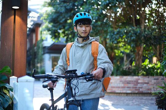 Asian food delivery rider walking with his bicycle