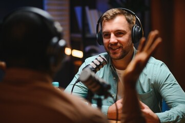 Man podcaster influencer blogger smiling while broadcasting his live audio podcast in studio using...