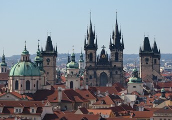Fototapeta premium Prague cityscape featuring towers, domes, and red rooftops under a clear sky