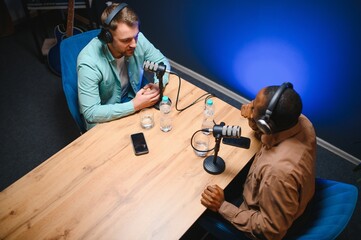 Man recording podcast using high tech microphones to interview guest, ensuring flawless video and...