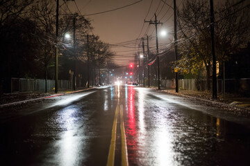 Abandoned street during blackout with reflections on wet pavement, dim emergency lights casting an eerie glow in the night