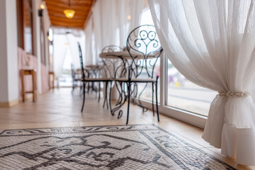 Elegant Mediterranean restaurant patio featuring light-filtering curtains, intricate tiled floor, and stylish wrought-iron furniture in a welcoming atmosphere