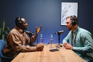Podcasters enjoying happy conversations with online listeners in studio, covering wide range of...