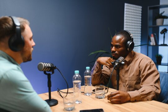Show host and guest meeting to stream podcast episode together, creating online content with live broadcast discussion. Vlogger talking to man using professional equipment to record chat