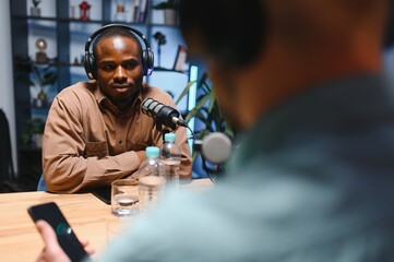 Show host and guest meeting to stream podcast episode together, creating online content with live broadcast discussion. Vlogger talking to man using professional equipment to record chat
