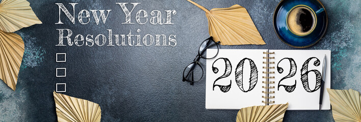 New year resolutions 2026 on desk. 2026 goals list with notebook, coffee cup, plant on wooden table. Resolutions, plan, goals, action, checklist, idea concept. New Year 2026 resolutions, copy space
