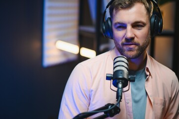 Man podcaster influencer blogger smiling while broadcasting his live audio podcast in studio using...
