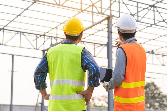 Team architect, colleague builder asian young male, man worker wearing safety helmet, using laptop computer discussing, inspecting reconstructed construction building renovation, check defect at site.